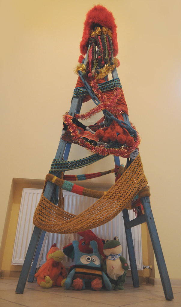 An improvized Cristmas tree made of a ladder decorated with knit scarves and crochet jewelry